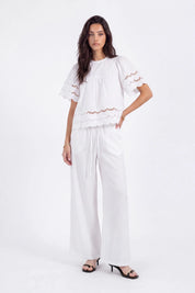 White Short-Sleeve Blouse with Cutwork Embroidery and Ruffled Hem on model, studio view 3 – Elppis 1B5E09174WW-01CM