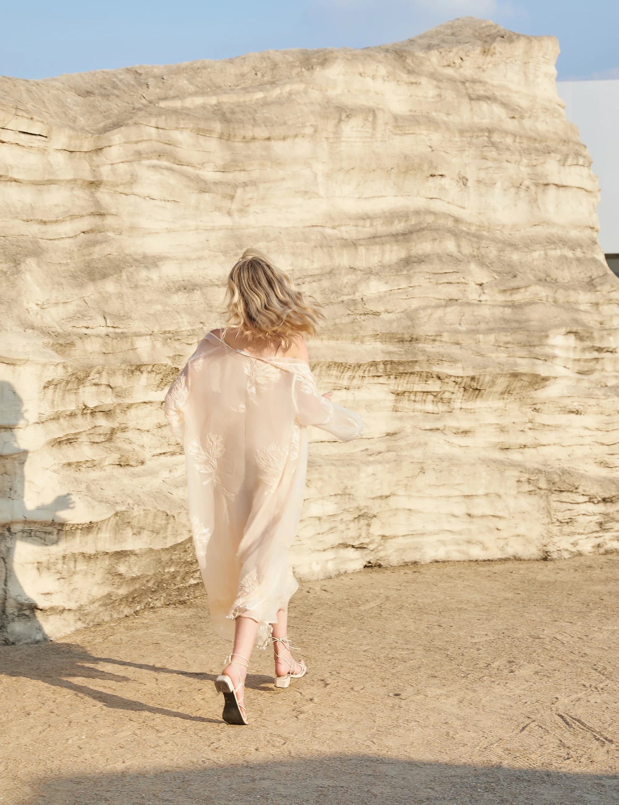 Back outdoor view of the Elppis blush pink sheer midi slip dress