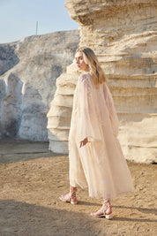 Resort setting view of the Elppis blush pink embroidered midi dress
