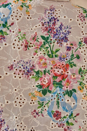 Close-up of the cream floral eyelet fabric and colorful botanical print
