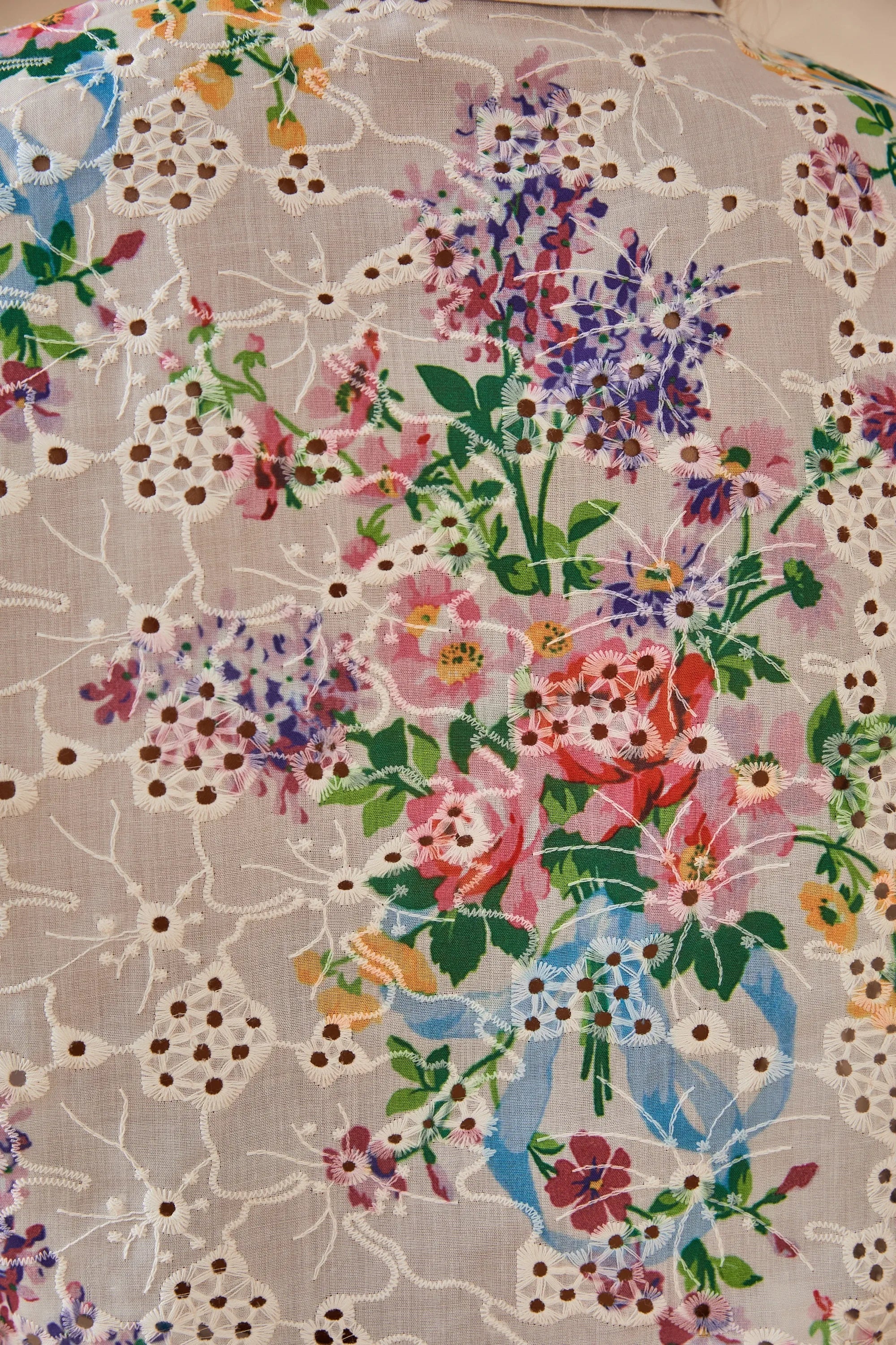 Close-up of the cream floral eyelet fabric and colorful botanical print